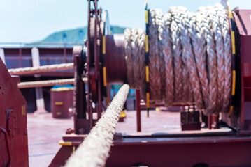 Large mooring winch on a ship's deck, featuring thick, braided ropes wound around a cylindrical metal drum. 