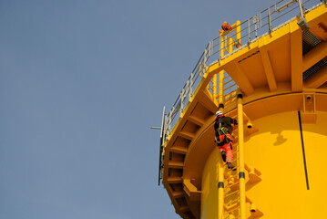 GWO-Certified Offshore Technician Rigger Climbing Wind Turbine Foundation Ladder Wearing Safety PPE.