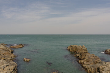 Rocky coastline landscape, natural style, blue and brown colors, tranquil ocean scene near Busan, South Korea, Haedong Yonggungsa Temple