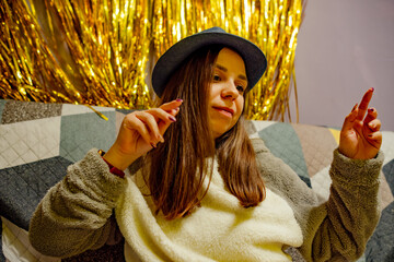 A woman wearing a blue hat is sitting on a couch, enjoying herself and dancing during a lively...