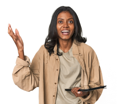 Young Indian woman with digital tablet receiving a pleasant surprise, excited and raising hands.
