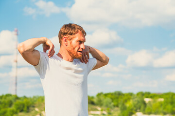 A professional sportsman in a white shirt is standing, holding his hands on his head as he performs...
