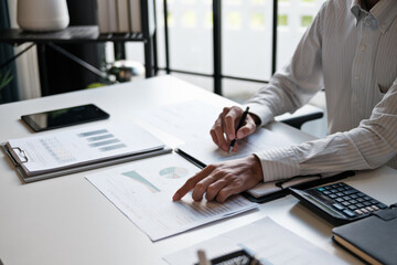 Administrative staff reviewing company budget report with calculator, document stack and focus at office desk