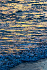 Wave on the ocean highlighted by the golden light of a sunset near the beach of La Parée in...
