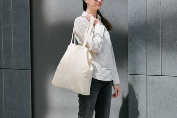 Woman walking in the city with a white tote eco bag