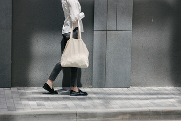 Woman walking in the city with a white tote eco bag
