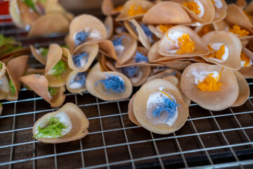 Colorful Khanom Buang, known as Thai crepe or crispy pancake with creamy topping made from egg whites and topped with egg yolk threads. It is a popular street food.