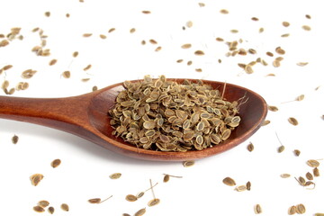 There is a pile of dill seeds on a wooden spoon.