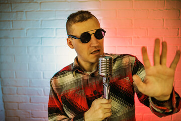 A man wearing a plaid shirt enthusiastically sings into a microphone, showcasing his passion for...