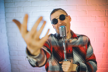 A man wearing a plaid shirt enthusiastically sings into a microphone, showcasing his passion for...