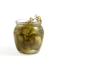 There is a glass jar with pickled cucumbers on a white background.	