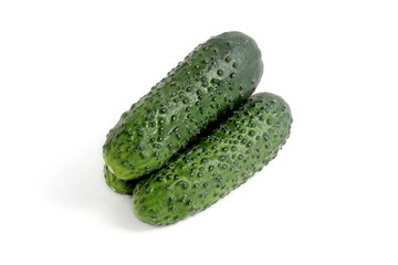 Three fresh green cucumbers lie on a white background.	
