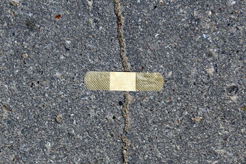 The crack in the asphalt was sealed with adhesive tape.