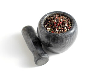 There are different types of peppercorns in a stone mortar.