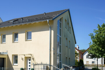 Modern residential building captured during bright daylight with clear blue sky and trees nearby
