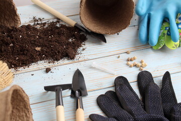 There is soil and accessories for seedlings on a wooden background.