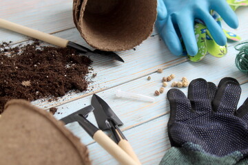 There is soil and accessories for seedlings on a wooden background.
