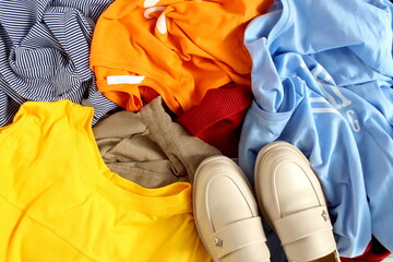 A lot of clothes are lying in the same pile with shoes.