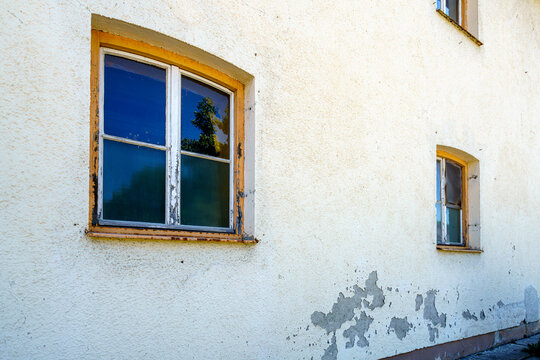 Weathered building wall with vintage windows under sunlight in a quiet neighborhood during the afternoon - Powered by Adobe