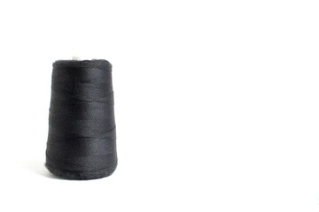 On a white background stands a large spool of black sewing thread.