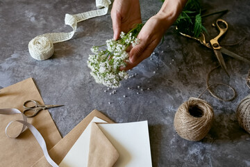Creating a rustic floral arrangement with natural materials on a textured surface in a cozy crafting space