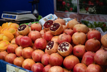 Large pile of pomegranates on counter of fruit market. bright juicy pomegranates as background. Close-up of a lot of ripe red pomegranates with specks on the market counter for sale