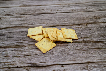 A pile of crispy, golden crackers rests on a weathered wooden table, perfect for enjoying with cheese or dips during a casual gathering or snack time