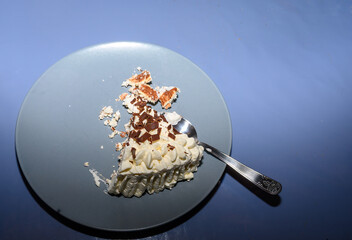 A lovely chocolate cake with creamy frosting shows visible signs of being enjoyed during a gathering. A fork rests beside the partially consumed dessert on a blue plate