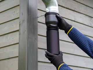 Flexible plastic rain gutter pipe installation. Rainwater collection for garden watering. Gutter extension for homes