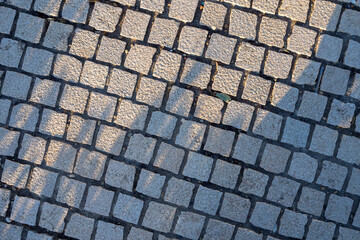 Natural stone paving with green moss in joints. Illustrates eco-friendly urban landscaping. Diagonal arrangement. Architectural background.