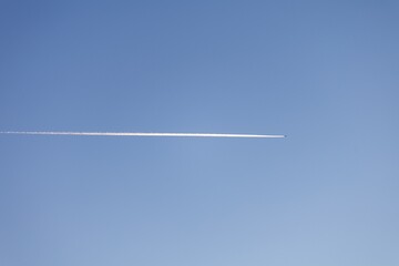 Serene Blue Sky with a Singular Contrail Painting the Horizon