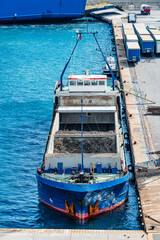 Cargo ship loaded with scrap metal docked at industrial port