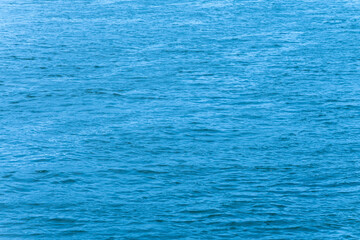 A calm sea surface with light waves against daylight is the perfect backdrop or texture.