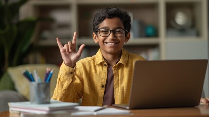 A young deaf Indian boy student engages in an online video call on his laptop, using sign language while focused on the screen