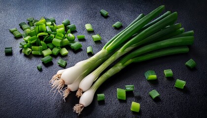 fresh green onion sprigs and chopped pieces on dark background for food and cooking use