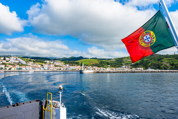 View of Horta port from ferry sailing to Pico island under Portuguese national flag, Faial island, Azores, Portugal