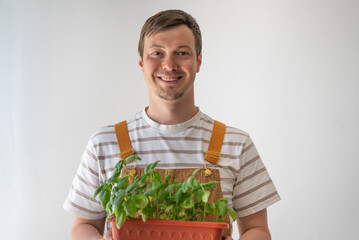 Happy gardener smiling while holding a pot filled with vibrant basil seedlings, showcasing home...