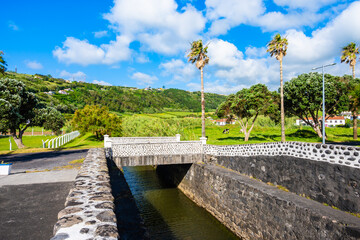 Coastal promenade with aplm trees along Almoxarife beach with azure ocean water, Faial island, Azores, Portugal
