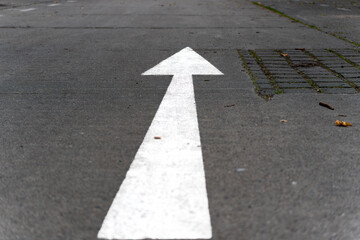 Straight-ahead arrow on asphalt. A white directional arrow is clearly visible on the asphalt of a...
