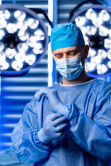 Surgeon prepping for surgery. A medical professional puts on surgical gloves while preparing for a...