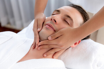 Obraz premium Caucasian man enjoying relaxing anti-stress head massage and pampering facial beauty skin recreation leisure in dayspa modern light ambient at luxury resort or hotel spa salon. Quiescent