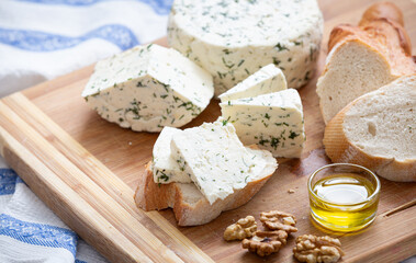 Homemade organic white cheese served with crispy bread, walnut and olive oil on wooden board on the table. Healthy food, snack and eating.