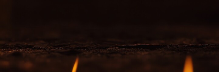 Two flickering flames glow softly against a dark, textured backdrop, casting warm light and creating an intimate, inviting atmosphere filled with quiet warmth and mood