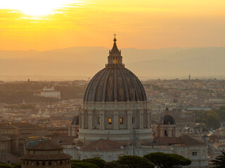 Aerial sunrise view of Vatican dome dominating central Rome, with Renaissance detail, glowing sky and scenic landscape in soft golden tones. Stunning silhouette of St. Peter’s Basilica. Travel