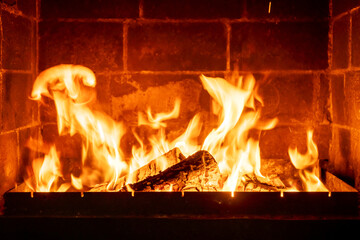 Burning fireplace logs with high flames inside brick hearth, cozy interior warmth, traditional home heating, rustic ambiance, romantic cabin atmosphere, winter season comfort, firewood crackling sound