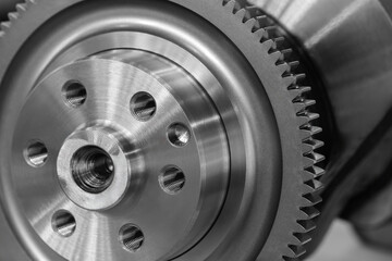 A close up of a gear with many holes. The gear is silver and has a black rim industrial concept background