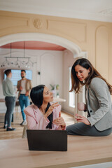 Businesswomen discussing work in modern office with laptop
