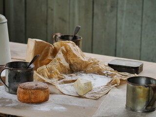 Vintage kitchen table with pork pie and aged cheese in parchment paper.