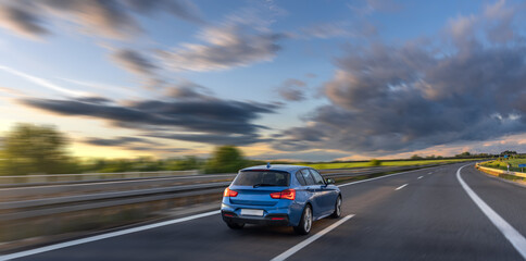 Red car on highway. Sunset drive. Motion on road
