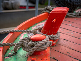 Close-up of a mooring rope tied to an red boat cleat on a vibrant painted deck.